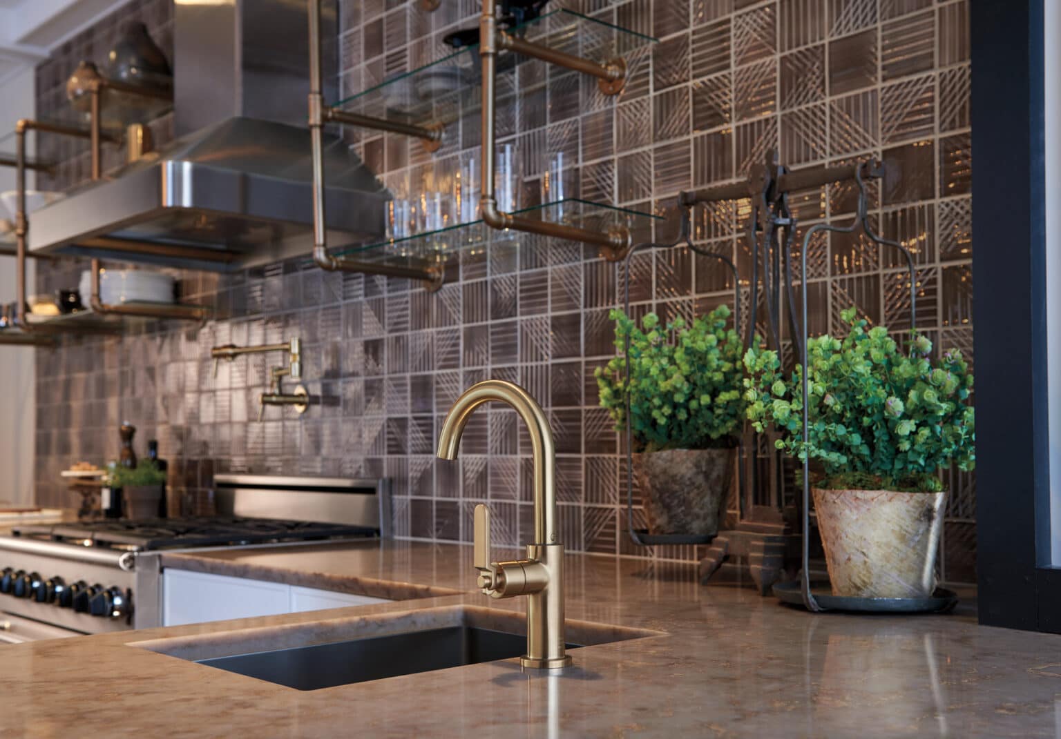 The Brizo Litze bar faucet in Luxe Gold features an arc spout and a knurled industrial handle over a dark countertop.