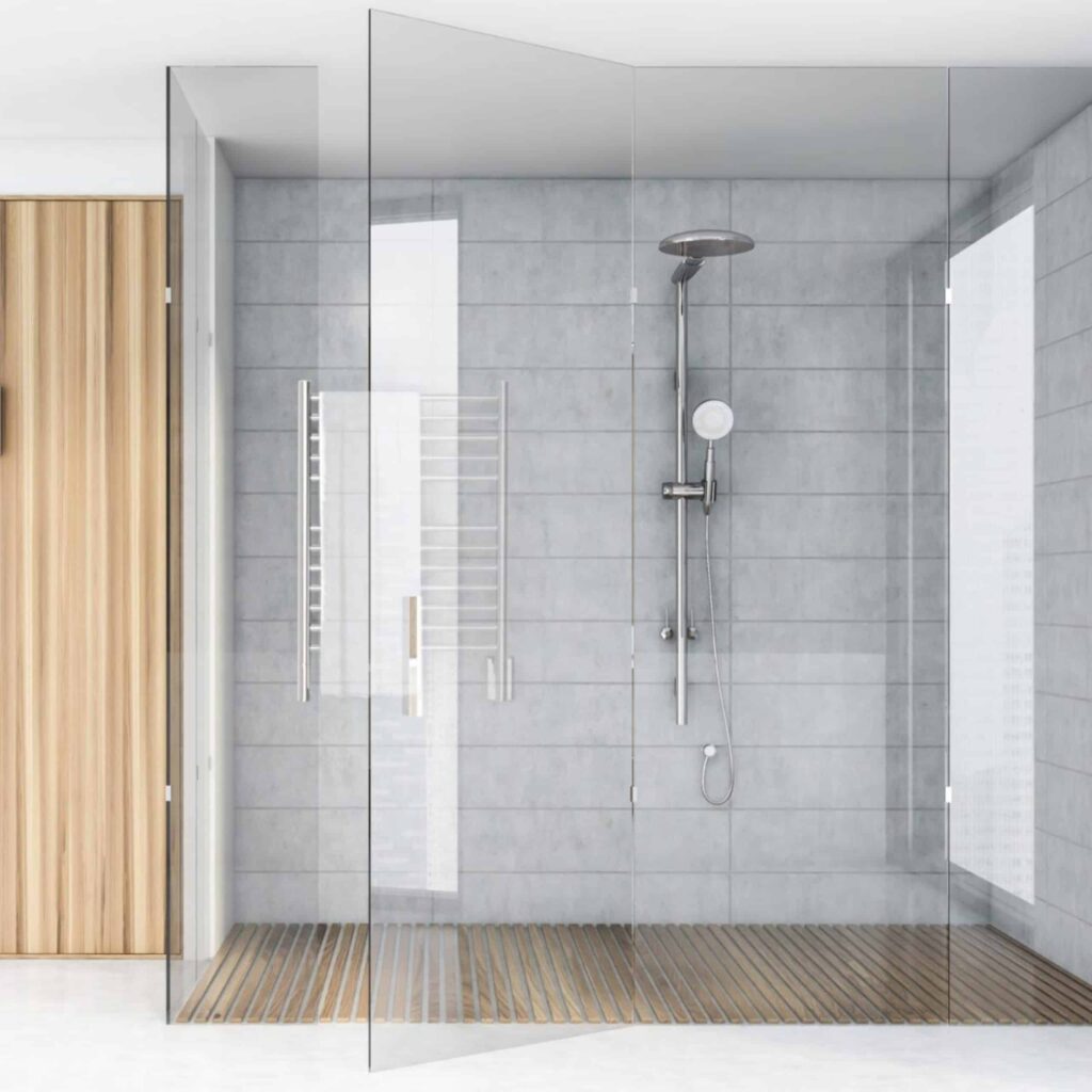 Modern walk-in shower with gray tile, a wood slat floor, a chrome shower system, and a wall-mounted electric towel warmer.